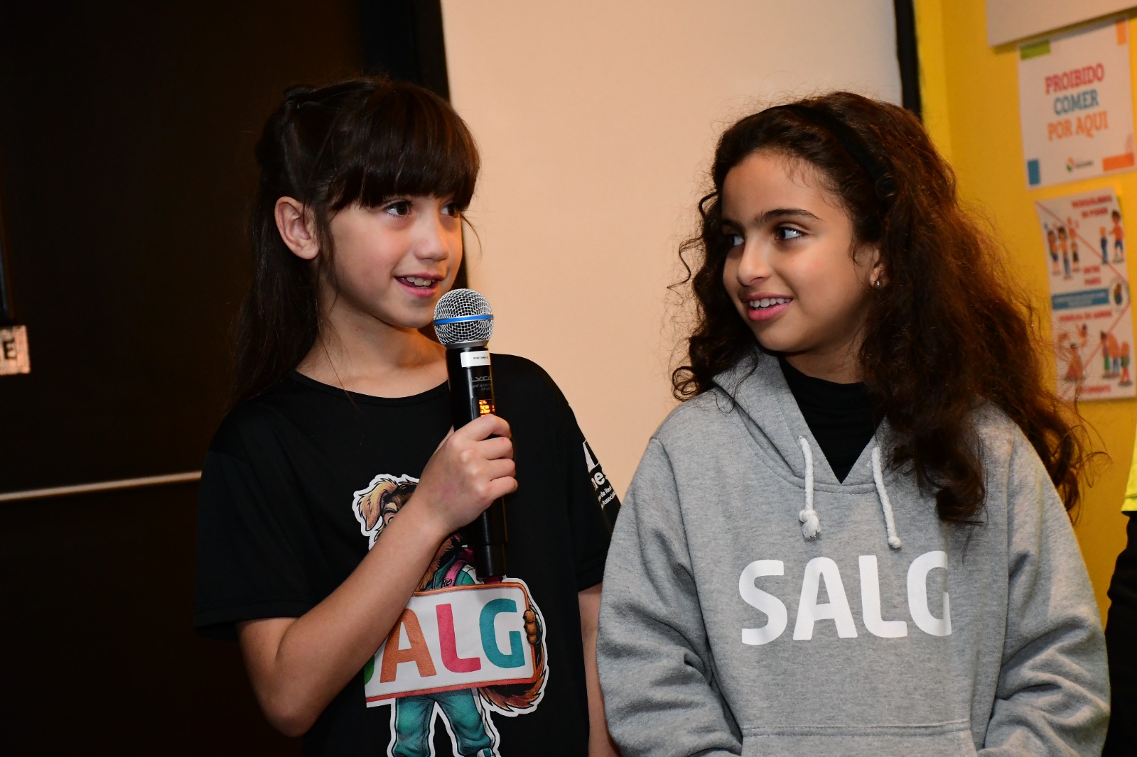 Duas alunas apresentando o projeto solidário ao microfone na Fecusa