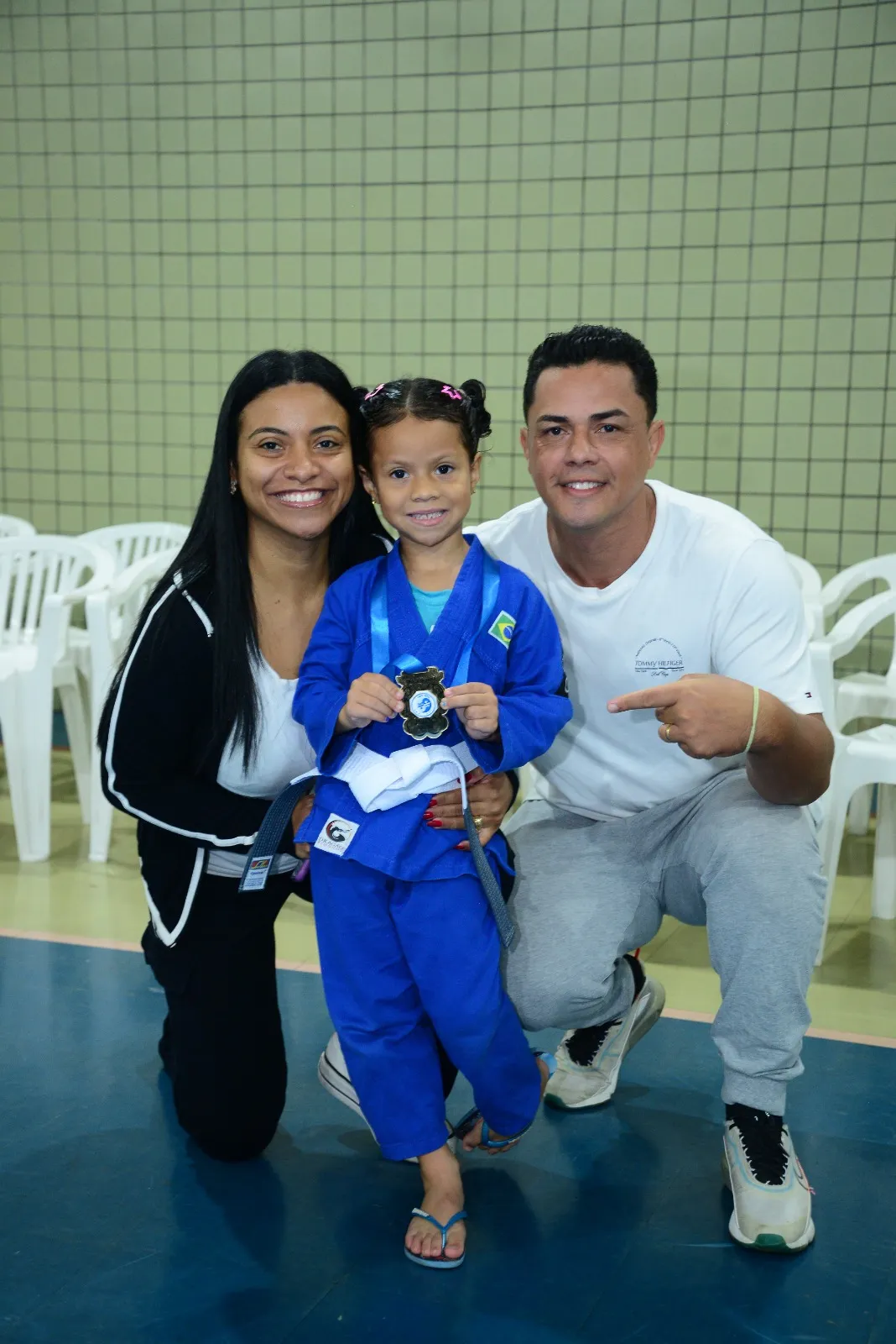 Aluna com medalha comemora a troca de faixa ao lado da família — Troca de Faixa de Judô, Colégio Salgueiro em Interlagos