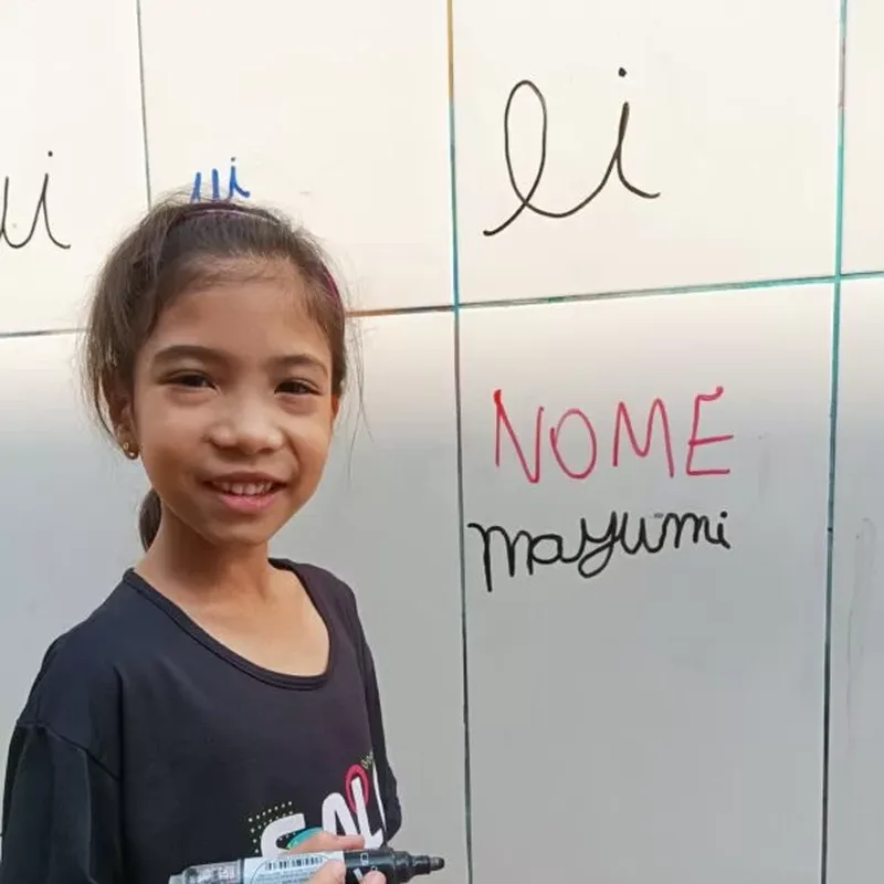 Aluna escrevendo o próprio nome no azulejo com caneta apagável