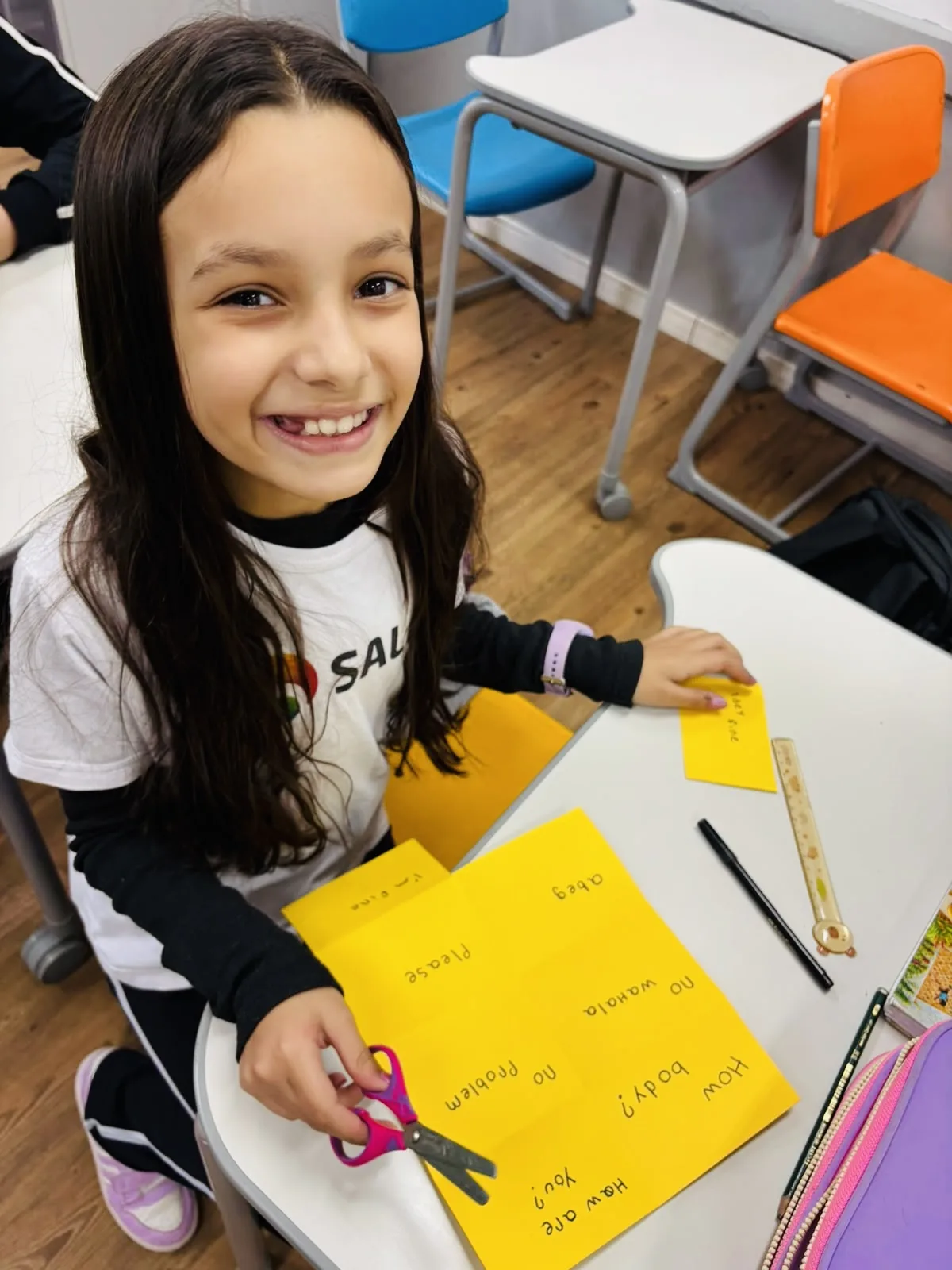 Estudante recorta cartões com expressões em inglês durante atividade do Projeto Antirracista